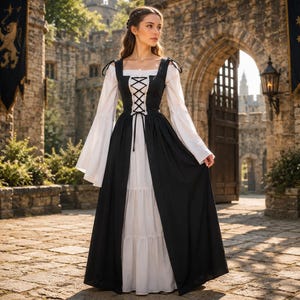 May include: A floor-length dress featuring a white underlayer with long, flared sleeves and a black overlayer bodice with a lace-up front closure. The garment has a square neckline and black ribbon shoulder ties, creating a layered appearance.