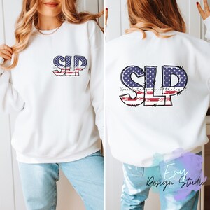 Puede incluir: Sudadera blanca con las letras "SLP" en un diseño patriótico en la parte delantera y trasera. Las letras están rellenas con un patrón de estrellas azules y rayas rojas, con las palabras "Logopeda" debajo.