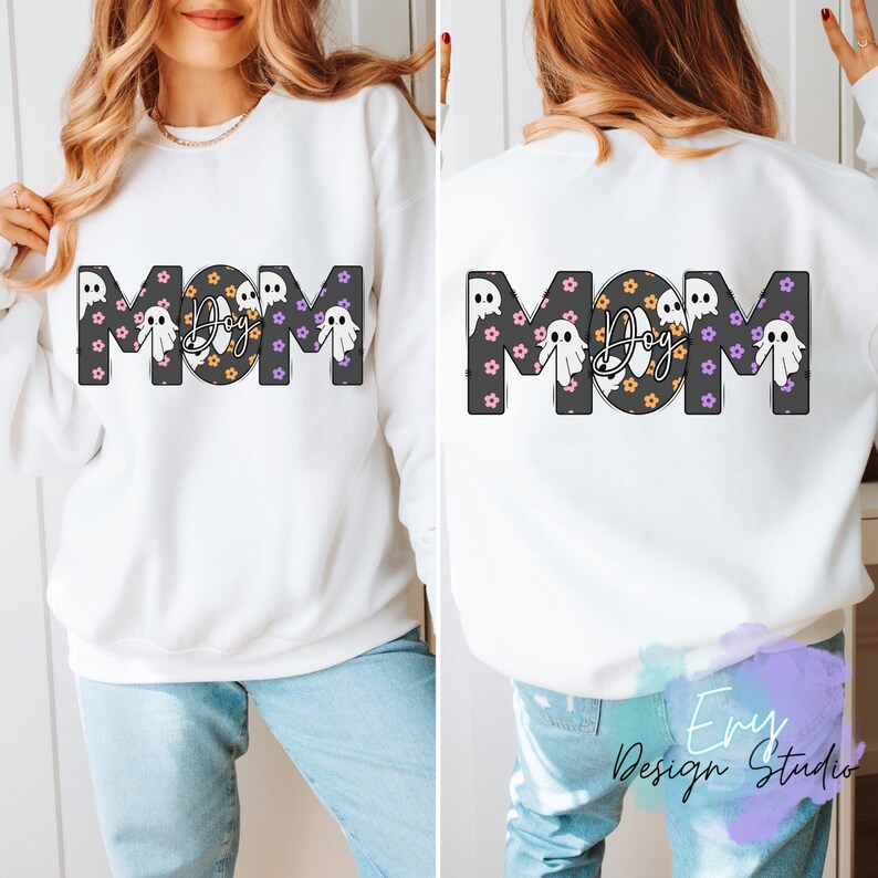 Pode incluir: Camisola branca com a palavra "MOM" em letras pretas delineadas com um padr&atilde;o de fantasmas e flores. O "O" de MOM &eacute; substitu&iacute;do por um c&iacute;rculo preto com a palavra "Dog" em branco dentro.