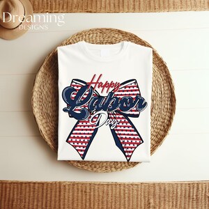 Pu&ograve; includere: T-shirt bianca con un design patriottico per la festa del lavoro. Il design presenta un grande fiocco con strisce rosse e bianche e stelle blu, e le parole "Happy Labor Day" in corsivo rosso e blu.