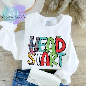May include: White sweatshirt with the words "HEAD START" in colorful, playful letters. The letters are decorated with school-themed patterns like pencils, apples, and numbers.
