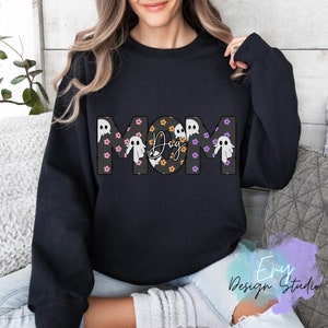 Pode incluir: Camisola de moletom preta com a palavra "MOM" em letras grandes, com um padr&atilde;o de fantasmas e a palavra "Boo" no "O".