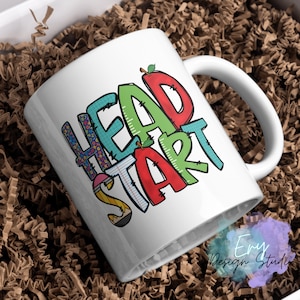 May include: White ceramic mug with a colorful graphic design that says "Head Start". The design includes a red apple, a pencil, a ruler, and a piece of notebook paper.