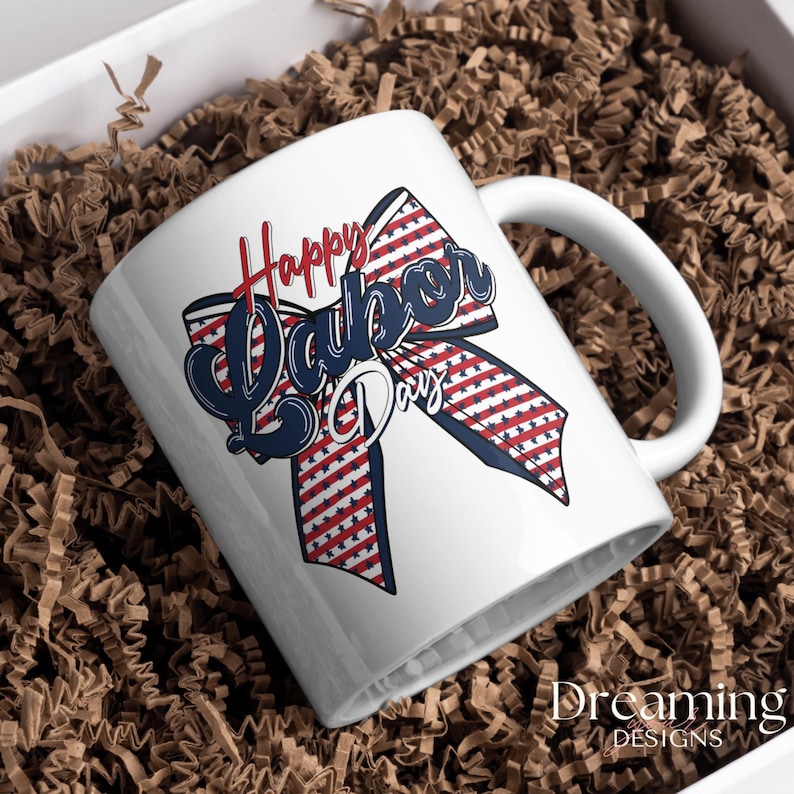 Pu&ograve; includere: Tazza in ceramica bianca con un design patriottico. La tazza presenta un nastro rosso, bianco e blu con stelle e strisce, e le parole "Happy Labor Day" in un carattere corsivo. La tazza &egrave; in una scatola bianca con materiale di imballaggio marrone.