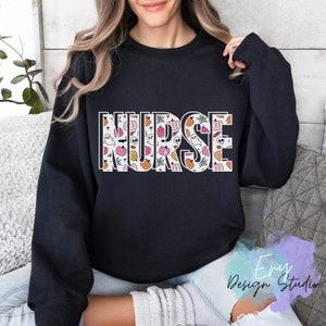 Puede incluir: Sudadera negra con la palabra "NURSE" en letras grandes con contorno blanco. Las letras est&aacute;n rellenas con un patr&oacute;n de calabazas, fantasmas y telara&ntilde;as en naranja, rosa y blanco. Un dise&ntilde;o tem&aacute;tico de Halloween.