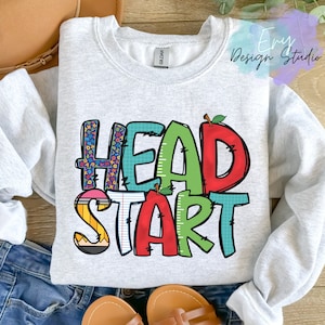 May include: A gray sweatshirt with the words "Head Start" in colorful letters. The letters are decorated with images of pencils, rulers, and apples.