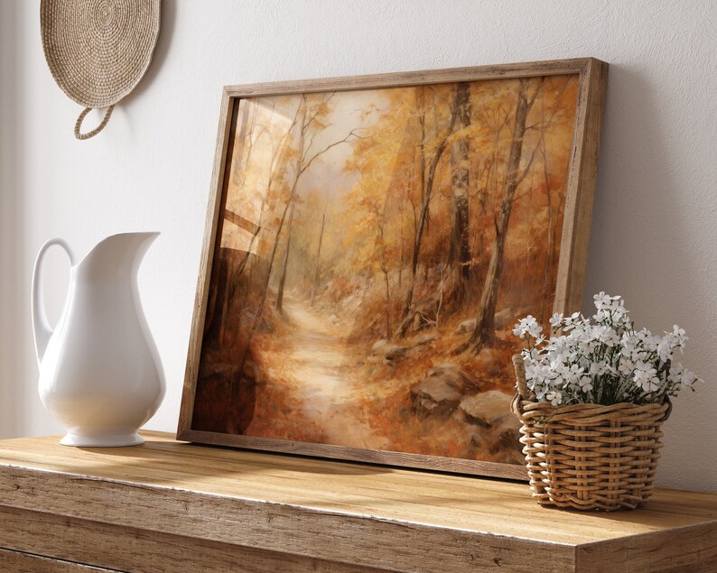 May include: A framed painting of a forest path with autumn leaves in shades of yellow, orange, and brown. The path leads into the distance, surrounded by trees.