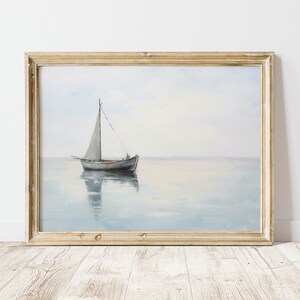 May include: A framed painting depicting a sailboat on a calm, blue sea. The sailboat has a white sail and is sailing towards the horizon. The painting is in a light wood frame.