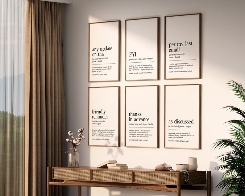 May include: Six framed prints with black text on a white background. The prints feature the definitions of common office phrases like "any update on this", "FYI", "per my last email", "friendly reminder", "thanks in advance", and "as discussed".
