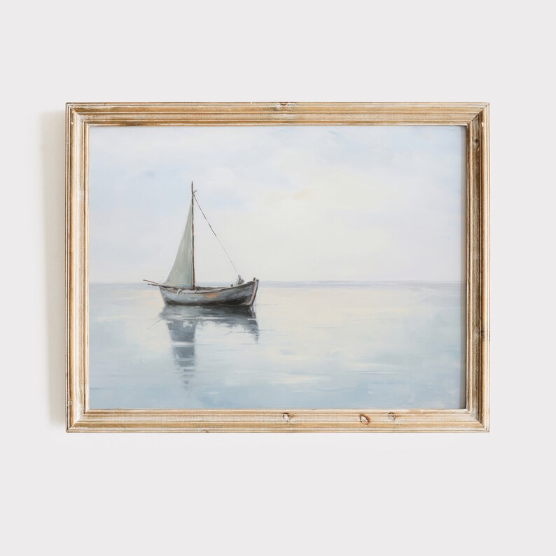 May include: A framed painting depicting a sailboat on a tranquil, blue expanse of water. The sailboat features a white sail and is positioned centrally in the image. The sky is a pale blue with a touch of pink in the distance.