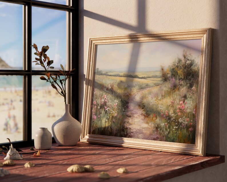 May include: A framed painting of a rural landscape with a dirt path leading through a field of wildflowers. The painting is in a light wood frame and is hanging on a wall.