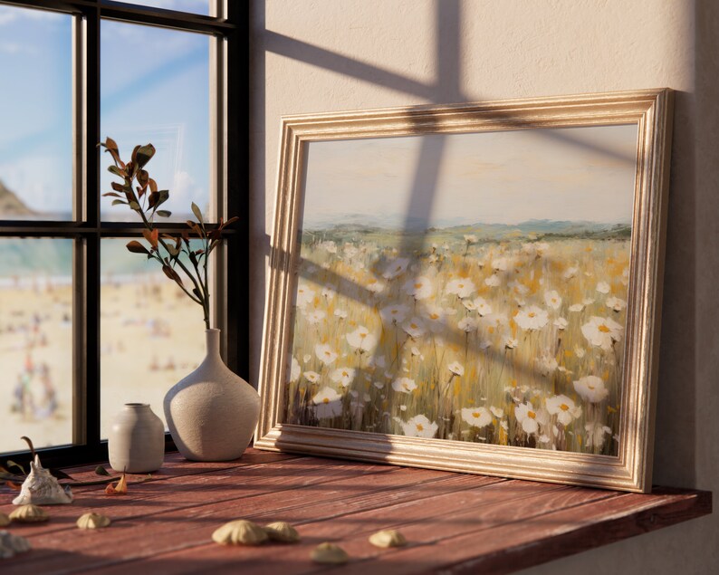 May include: A framed painting of a field of white wildflowers with a light blue sky in the background. The painting is on a wooden table with a vase of dried branches and two smaller vases.