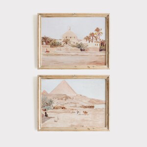 Puede incluir: Dos pinturas enmarcadas que representan escenas de Egipto. La pintura superior muestra una mezquita con palmeras en el fondo. La pintura inferior muestra las pir&aacute;mides con personas y camellos en primer plano.