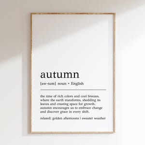 Può includere: Una stampa d'arte da parete stampabile con la definizione della parola "autunno" in testo nero su sfondo bianco. La definizione include la pronuncia, la categoria grammaticale e le parole correlate. La stampa è incorniciata in una cornice di legno chiaro.