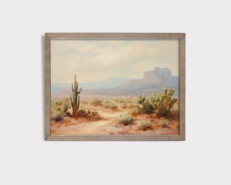 May include: A framed painting of a desert landscape with a tall cactus and smaller cacti in the foreground. The background features a mountain range and a cloudy sky.