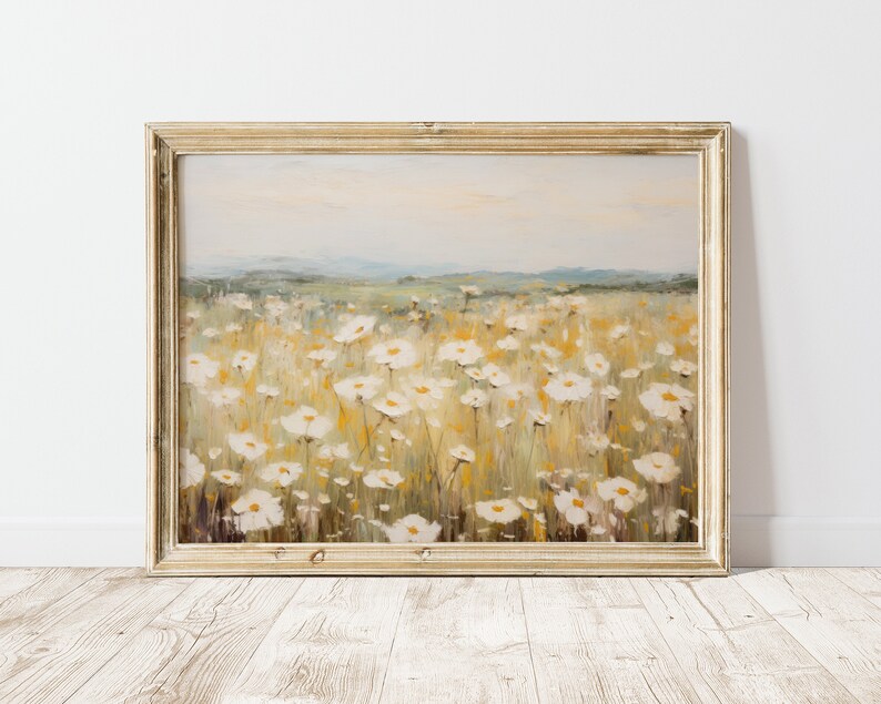 May include: A framed painting of a field of white wildflowers with a blurred background of a distant landscape. The painting is done in a soft, impressionistic style with muted colors.