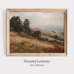 Op de afbeelding: Een ingelijst landschapsschilderij toont een kustlandschap met glooiende heuvels, bomen en een bewolkte lucht. Het kunstwerk gebruikt warme tinten bruin, goud en groen, met de tekst "DreamyLemony Art Collection" onderaan.