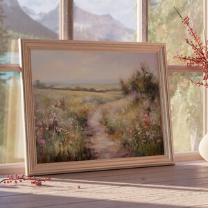May include: A framed painting of a landscape with a dirt path leading through a field of wildflowers. The painting is in a light wood frame and is hanging on a wall.