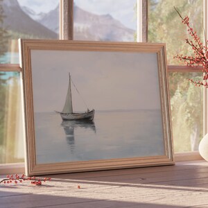 May include: A framed painting depicting a sailboat on a calm body of water. The painting is in a light wood frame and is hanging on a wall.