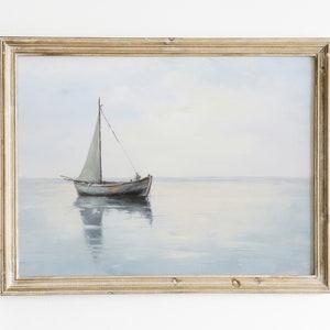 May include: A framed painting depicting a sailboat on a tranquil, blue expanse of water. The sailboat features a white sail and is positioned centrally in the image. The sky is a pale blue, while the water is a light blue with a subtle hint of grey.