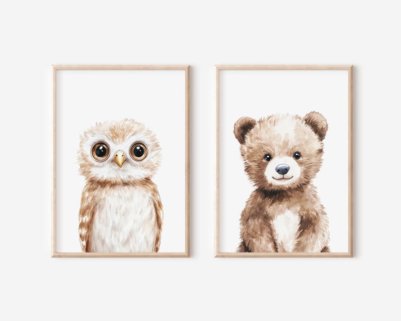 May include: Two framed watercolor prints featuring adorable woodland creatures. One print showcases a wide-eyed owl with brown and white feathers. The other print depicts a cute brown bear with a white chest and a sweet expression. Both are framed in light wood.