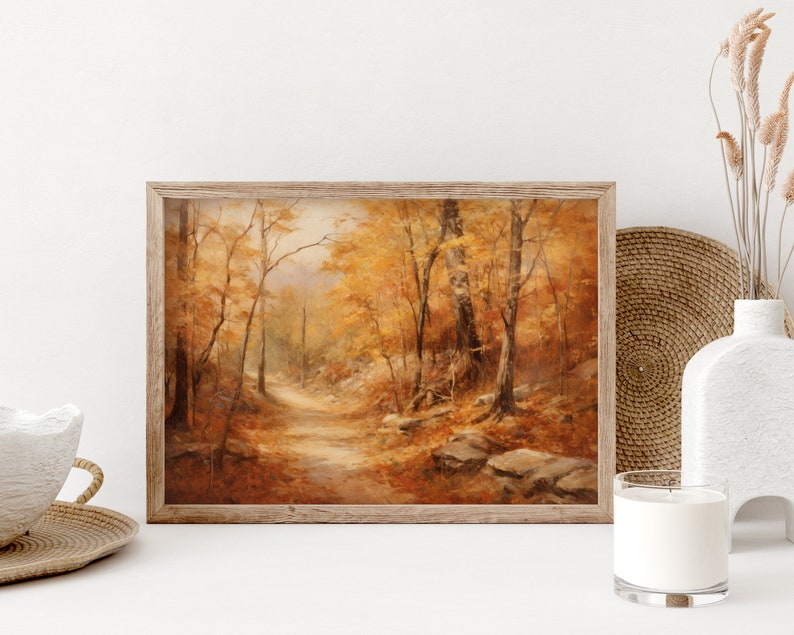 May include: A framed painting of a forest path in autumn. The trees are a mix of yellow, orange, and brown, and the path is lined with fallen leaves. The painting is set against a white background.