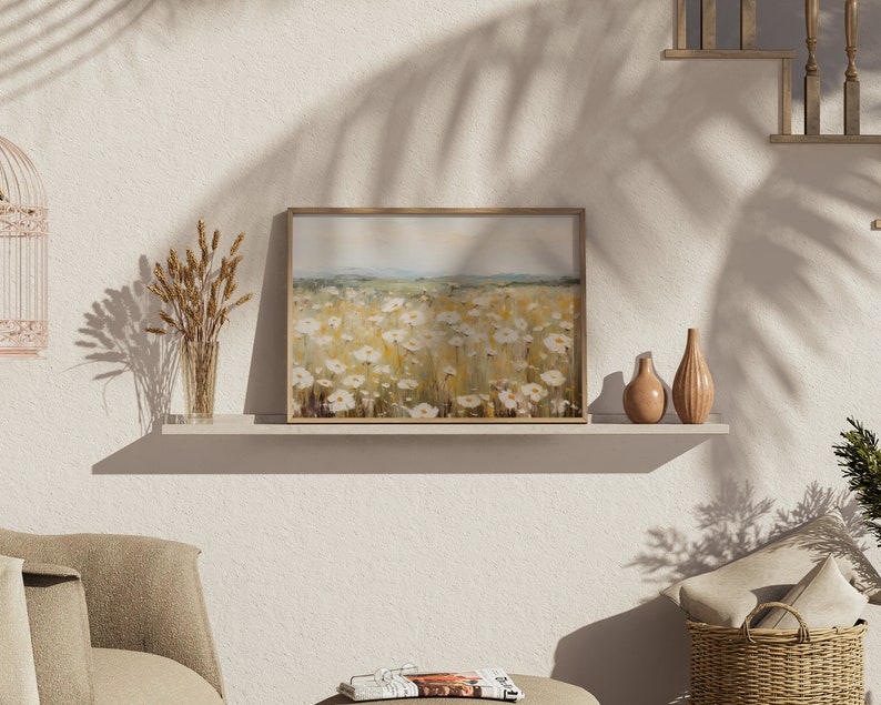 May include: A framed painting of a field of white wildflowers with a light blue sky in the background. The painting is on a shelf with two decorative vases and a vase of dried wheat.