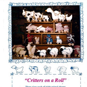 May include: A set of eight different animal shapes on wheels, each in three sizes. The animals are a cow, a goose, a bunny, a chick, a sheep, a cat, a dog, and a pig. The animals are made of fabric and have a whimsical, handmade look. The caption reads "Critters on a Roll" and includes the text "Three sizes each of eight animal shapes. 2 inches to 4-1/2 inches tall. Many other creative uses. * See back cover *"