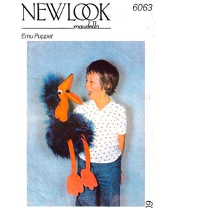 May include: A New Look Emu Puppet pattern. The puppet is a whimsical bird with a blue feathery body, orange beak and legs, and a large, expressive eye. The puppet is held by a child.