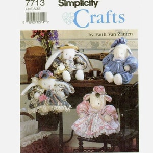 Peut inclure: Un patron de couture Simplicity Crafts pour réaliser quatre jouets en peluche. Le patron comprend des instructions pour réaliser un lapin portant une robe bleu et blanc, un lapin portant une robe rose et blanc, un agneau portant une robe bleue et un agneau portant une robe rose. Le patron est intitulé "Crafts" et est de Faith Van Zanten.