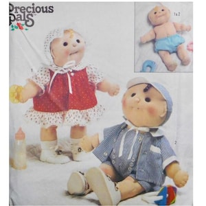 May include: A sewing pattern for making two dolls. The pattern includes instructions for making a girl doll wearing a red and white dress and a boy doll wearing a blue and white striped outfit. The pattern is from Precious Pals.