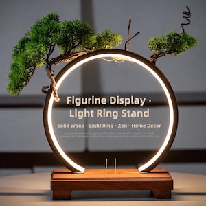 May include: A decorative figurine display stand with a light ring and a small bonsai tree. The stand is made of solid wood and features the text "Figurine Display • Light Ring Stand". The design incorporates Zen elements.