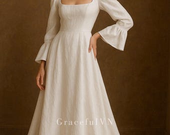 May include: A white wedding dress with a square neckline and long sleeves with flared cuffs. The dress has a fitted bodice and a flowing skirt that trails on the floor. The text "Graceful VN" is visible on the lower part of the dress.