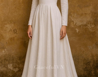 May include: A long, ivory-colored dress with a square neckline and long sleeves. The dress has a fitted bodice and a flowing skirt. The text "GracefulVN" is visible at the bottom. The dress is made of a textured fabric.