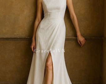 May include: A sleeveless white wedding dress with a boat neckline and a high slit. The dress has a fitted bodice and a flowing skirt that pools on the floor. The text "Graceful VN" is visible on the dress.