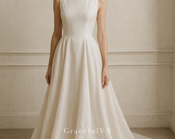 May include: A sleeveless, ivory-colored wedding dress with a boat neckline and a full skirt. The dress has a fitted bodice and a flowing skirt that trails on the floor. The text "GracefulVN" is visible on the skirt.