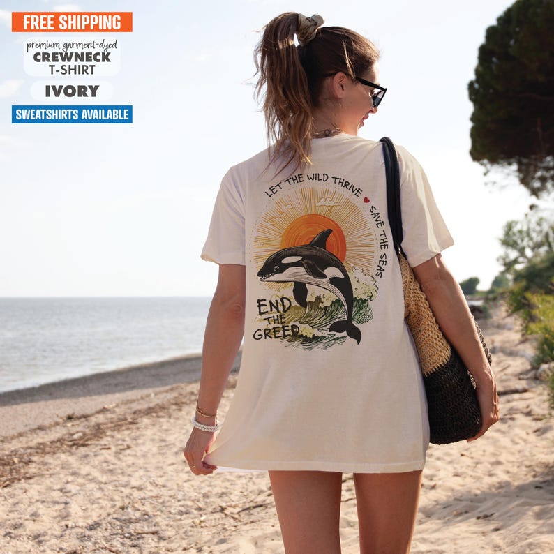 May include: White t-shirt with a graphic of an orca jumping out of the water with a sunset in the background. The text "Let the wild thrive save the seas" is printed on the shirt. The text "End the greed" is printed below the orca.