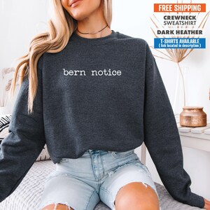 May include: Dark heather grey crewneck sweatshirt with the text "bern notice" in white lettering.