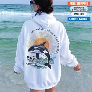 May include: White hoodie with a graphic of a killer whale jumping out of the water with a sun and the text "Let the wild thrive save the seas end the greed".