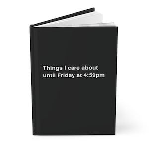 May include: A black journal with the text "Things I care about until Friday at 4:59pm" in white. The journal is open, revealing white pages. The cover is solid black.