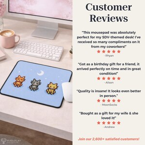 May include: A light blue mousepad featuring three pixelated cats and a crescent moon design. The mousepad is rectangular with a black border. The text "Customer Reviews" is visible in the image.