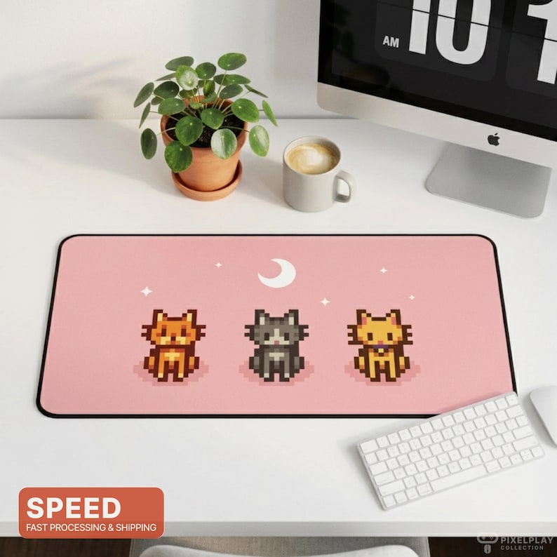 May include: A pink rectangular desk mat featuring three pixelated cat illustrations, a crescent moon, and stars. The mat has a black border and is next to a white keyboard and mouse. The word "SPEED" is in a red box.