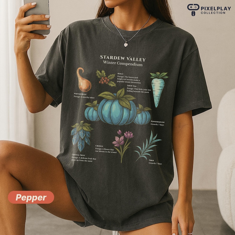 May include: Dark gray t-shirt featuring a botanical illustration from Stardew Valley's Winter Compendium. The design includes blue pumpkins, a parsnip, and other winter crops. The text "Pepper" is at the bottom.