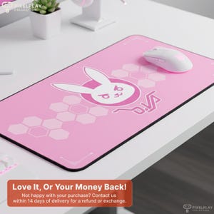 May include: Pink rectangular mousepad with a black border, featuring a white bunny logo and the word "D.Va" in pink. A white wireless mouse sits on the pad. The mousepad has a hexagonal pattern design. The text "Love It, Or Your Money Back!" is at the bottom.