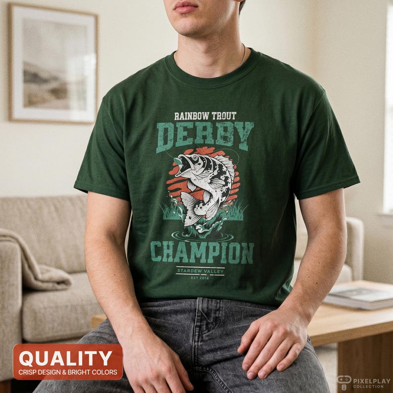Pu&ograve; includere: T-shirt verde scuro con una grafica di una trota iridea che salta fuori dall'acqua, con le parole "Rainbow Trout Derby Champion" in un font invecchiato. La maglietta ha anche il testo "Stardew Valley Est 2016".