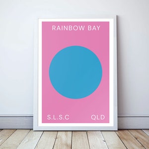 May include: A pink and blue minimalist poster with the text "RAINBOW BAY" in white, "S.L.S.C" in white, and "QLD" in white.