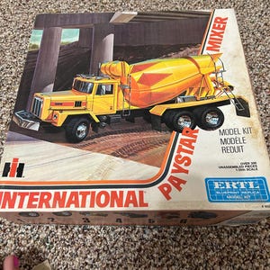 Puede incluir: Un kit de modelo Paystar Mixer amarillo y naranja de International. La caja presenta una ilustración del camión bajo un puente. El kit incluye más de 300 piezas sin montar a escala 1/25.