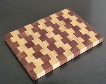 May include: A rectangular end-grain cutting board with a checkerboard pattern. The board is made of alternating blocks of light and dark wood, creating a visually appealing design. The board is approximately 12 inches long and 8 inches wide.