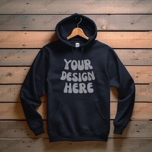 May include: A black hooded sweatshirt with a white graphic that says "YOUR DESIGN HERE" on a wooden background.