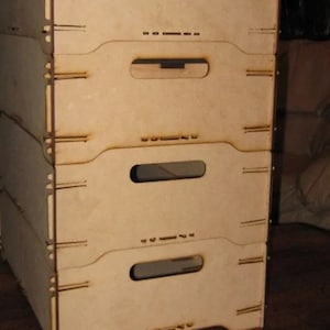 May include: A set of four wooden crates stacked on top of each other. The crates are made of light brown wood and have a simple design. Each crate has a small handle on the front.